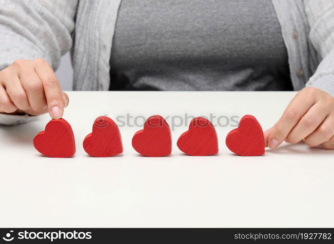 Customer experience feedback concept. Five red hearts, the best rating of excellent services with a female hand to meet. White table