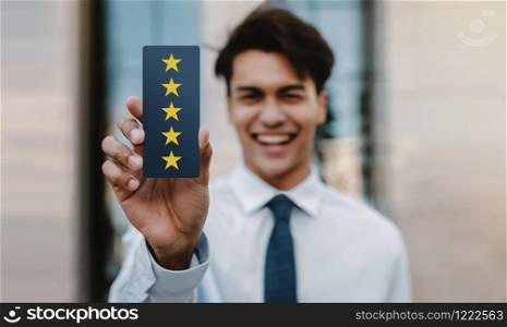 Customer Experiences Concept. Happy Young Businessman Giving Five Stars Rating and Positive Review on Card. Client&rsquo;s Satisfaction Surveys. Front View