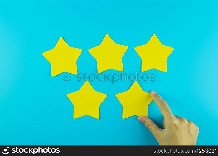 customer holding five star yellow paper note on blue background. Customer reviews, feedback, rating, ranking and service concept.