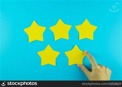 customer holding five star yellow paper note on blue background. Customer reviews, feedback, rating, ranking and service concept.