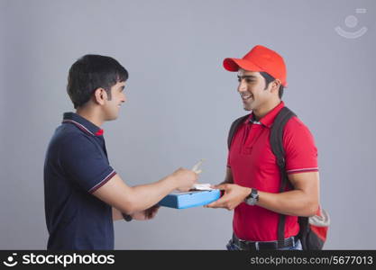 Customer paying pizza delivery man against gray background