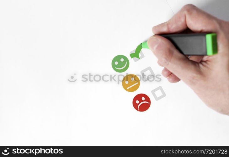 Customer satisfaction happy feedback rating checklist and excellent business quality evaluation concept with a customer hand checking a green smiling emoticon face icon top view with white copy space.