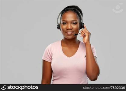 customer service, communication and people concept - smiling african american woman in headset with microphone over grey background. african american woman in headset with microphone