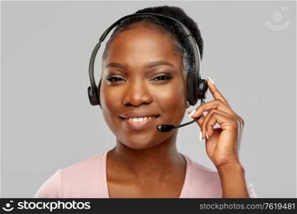 customer service, communication and people concept - smiling african american woman in headset with microphone over grey background. african american woman in headset with microphone