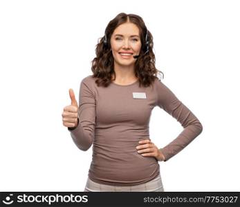 customer service, sale and business concept - happy female helpline operator or shop assistant with headset and name tag showing thumbs up over white background. shop assistant with headset showing thumbs up