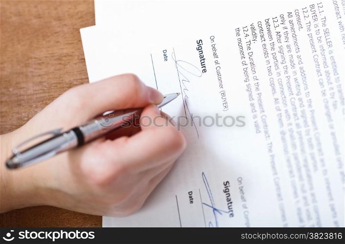 customer signs a contract by silver pen on table