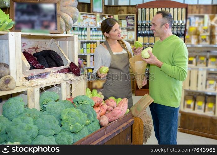 Customer talking to shop assistant while buying vegetables