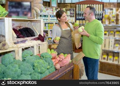 Customer talking to shop assistant while buying vegetables