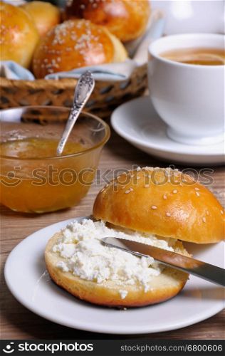 Cut bun with cottage cheese on a plate and a knife