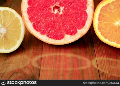 cut grapefruit orange and lemon are reflected on the surface. cut grapefruit orange and lemon are reflected on the wooden surface. juicy citrus fruits