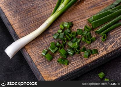 Cut Green onions chives on a cutting board. Dark concrete background. Fresh green onions on a cutting board. Dark concrete background
