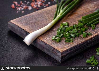 Cut Green onions chives on a cutting board. Dark concrete background. Fresh green onions on a cutting board. Dark concrete background