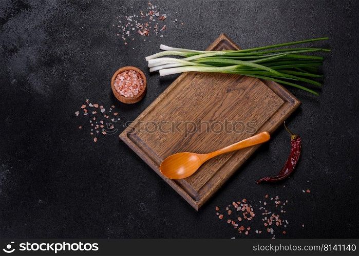 Cut Green onions chives on a cutting board. Dark wooden background. Top view of spring onions bunch ready to cutting on chopping board