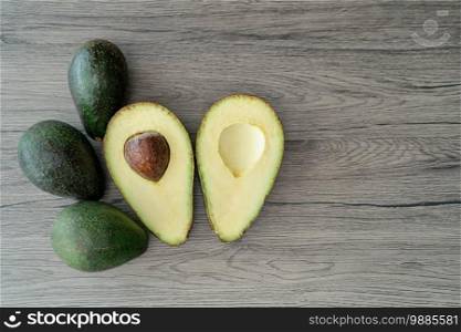 Cut half, sliced fresh green avocado on brown wooden table. Fruits healthy food concept.