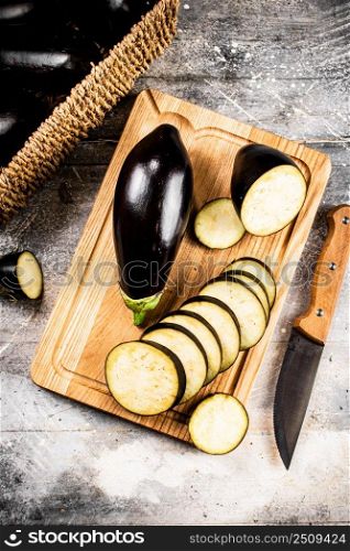 Cut into pieces of ripe eggplant on a wooden cutting board. On a gray background. High quality photo. Cut into pieces of ripe eggplant on a wooden cutting board. 
