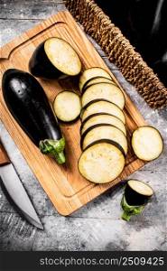 Cut into pieces of ripe eggplant on a wooden cutting board. On a gray background. High quality photo. Cut into pieces of ripe eggplant on a wooden cutting board. 