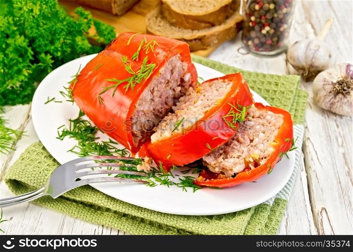 Cut into slices of bell peppers stuffed with meat and rice in a plate on a green napkin, fork, parsley on a wooden boards background