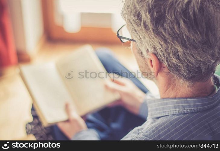 Cut out picture of a senior man who is reading a book at home