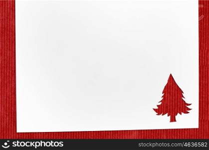 cut paper in fir-tree shape on table. Cut paper in christmas tree shape for christmas card or new year background on red table