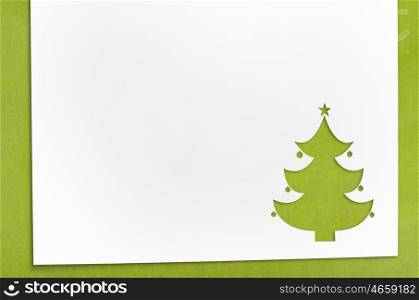 cut paper in fir-tree shape on table. Cut paper in fir-tree shape for christmas card or new year background on green table