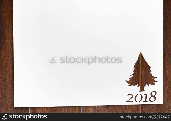 cut paper in fir-tree shape on table. Cut paper in fir-tree shape for 2018 christmas card or new year background on wooden table