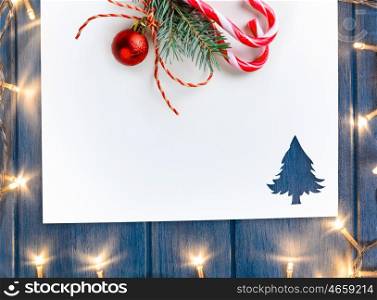 cut paper with lights in fir-tree shape on table. Cut paper in fir-tree shape with decorative lights for christmas card or new year background on blue wooden table