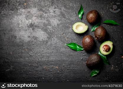 Cut ripe avocado with leaves. On a black background. High quality photo. Cut ripe avocado with leaves.