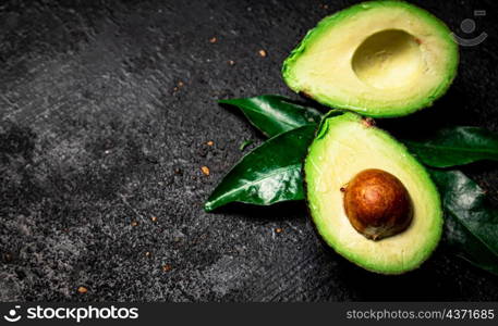 Cut ripe avocado with leaves. On a black background. High quality photo. Cut ripe avocado with leaves.