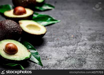 Cut ripe avocado with leaves. On a black background. High quality photo. Cut ripe avocado with leaves.