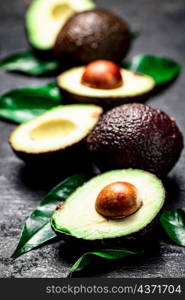 Cut ripe avocado with leaves. On a black background. High quality photo. Cut ripe avocado with leaves.