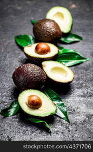 Cut ripe avocado with leaves. On a black background. High quality photo. Cut ripe avocado with leaves.