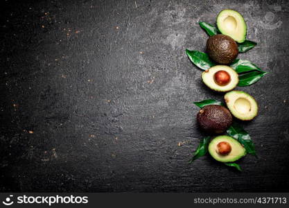 Cut ripe avocado with leaves. On a black background. High quality photo. Cut ripe avocado with leaves.