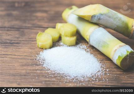 Cut sugar cane piece and white sugar on wooden background top view