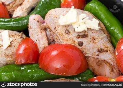 cut-up chicken, marinaded with spices in a roasting tin with vegetables, stock and a knob of butter,