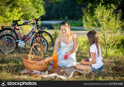 Cute 10 year old girl having picnic by the river with young mother
