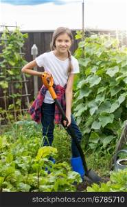 Cute 10 year old girl working at garden and digging soil at with shovel