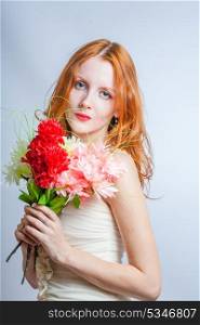 Cute 20s female with pretty flowers. Redhead women with bunch of flowers in studio on white. Blank expression.