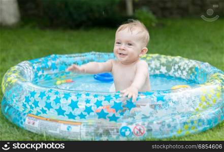 Cute 9 months old baby boy having fun in inflatable swimming pool