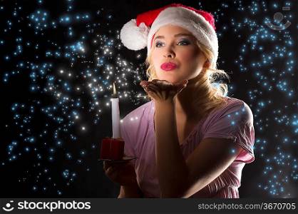 cute and attractive young woman with nightgown ant a christmas hat looking in the dark with a candle