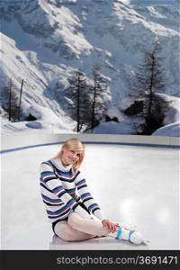 cute and blond girl with shorts and a nice sweater sitting with ice skates on over white