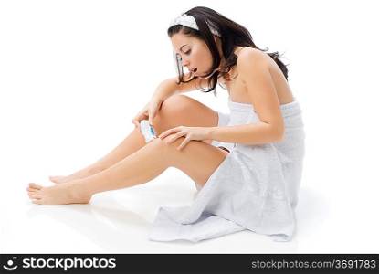 cute and young brunette dressing white towel shaving her legs and making face