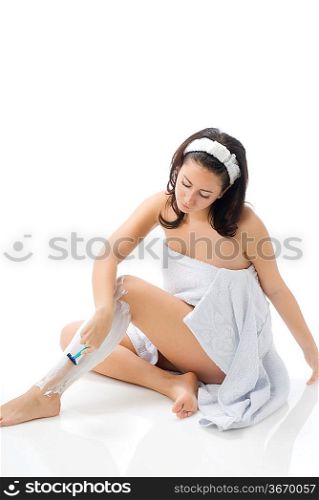 cute and young brunette dressing white towel shaving her legs with foam and making face