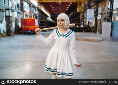 Cute anime style blonde girl with baseball bat. Cosplay fashion, asian culture, doll in dress, sexy woman with makeup in the factory shop. Cute anime style blonde girl with baseball bat