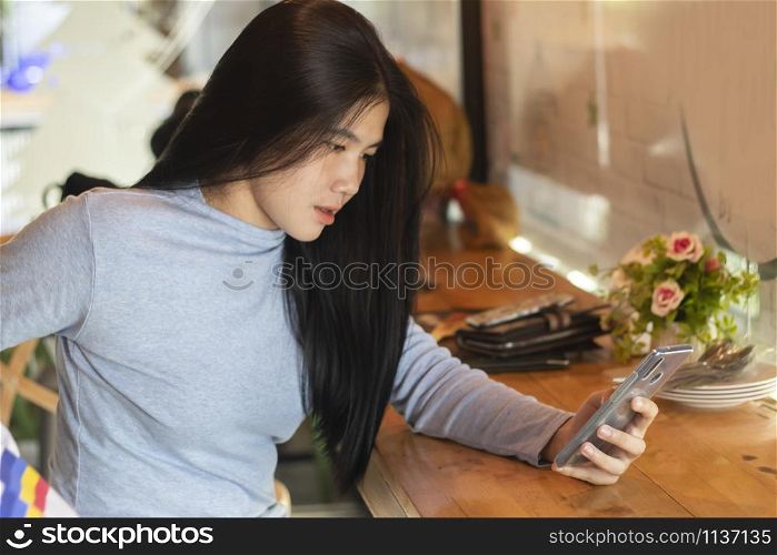 Cute asian girl holding smartphone in cafe