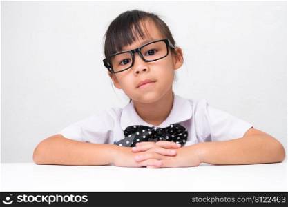 Cute Asian little girl playing teacher role game or a small businesswoman sitting on table in the office and looking at the camera. Homeschool children’s play and learning.
