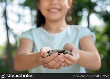 Cute asian little girl playing with coins money, child hand holding money. kid saving money into piggy bank. child counting his saved coins, children learning about for the future concept.