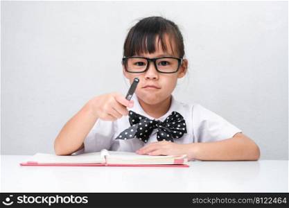Cute Asian little girl plays teacher role game or little businesswoman taking notes while working in the office. Homeschool children’s play and learning.