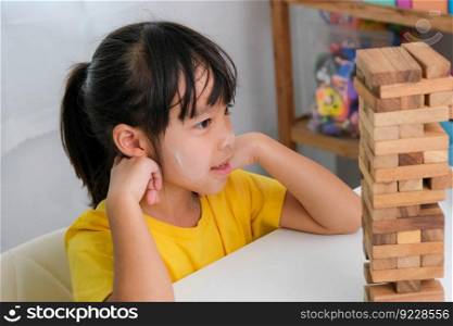Cute Asian siblings having fun playing Jenga together. Two children playing Jenga board game on table in room at home. Wooden puzzles are games that increase intelligence for children. Educational toys for children.