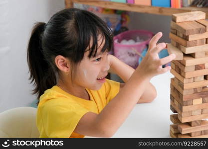 Cute Asian siblings having fun playing Jenga together. Two children playing Jenga board game on table in room at home. Wooden puzzles are games that increase intelligence for children. Educational toys for children.