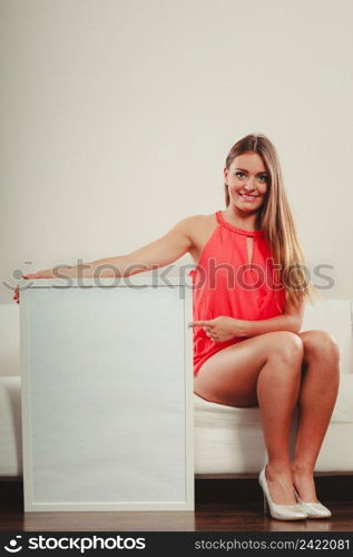 Cute attractive young woman girl in red shirt on sofa couch with blank empty white copy space banner. Summer female fashion vogue and advertisement.. Cute fashion woman with blank empty white banner.